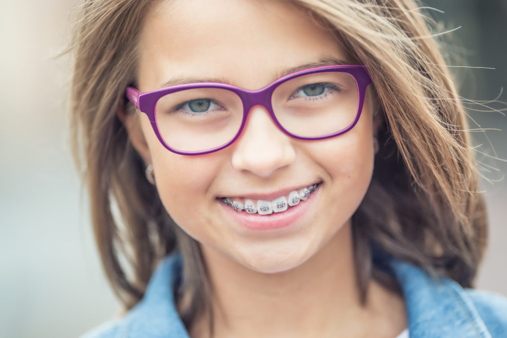 Portrait of happy young girl with dental braces and glasses.